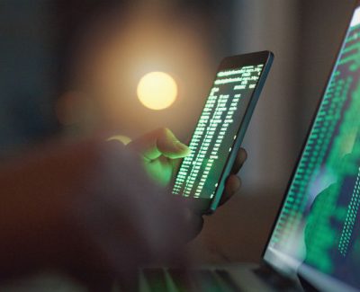 Hackers on laptop and phone performing a data breach