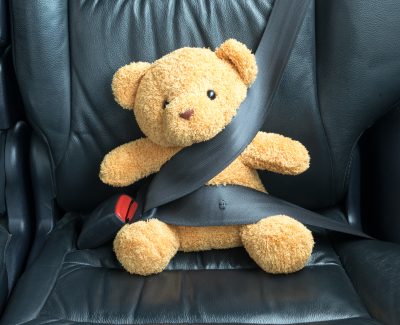 Teddy bear seat belted in a car seat