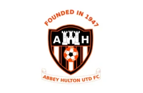 Abbey Hulton United FC crest featuring a black, orange, and white shield with a football and castle design, plus ‘Founded in 1947’ above the badge.